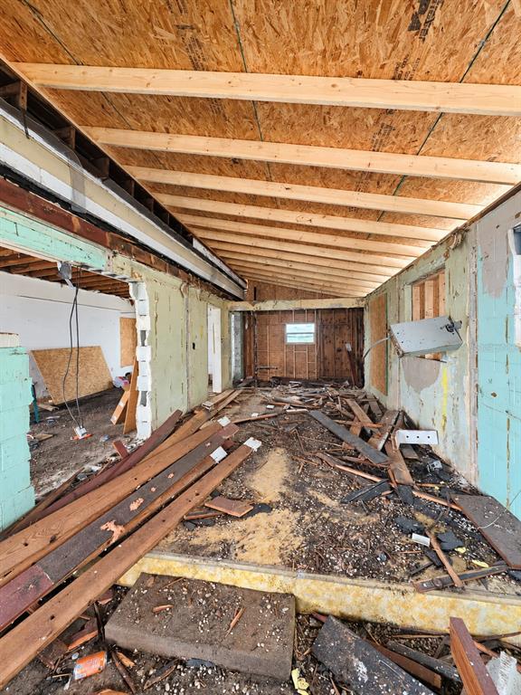 An interior view of a room under renovation with exposed ceiling joists and boarded windows — 1024 W FAIRBANKS AVENUE, ORLANDO, FL
