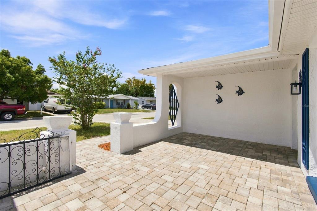 A paved patio area features a white stucco wall with decorative fish accents and railings — 7025 WESTCOTT DRIVE, PORT RICHEY, FL