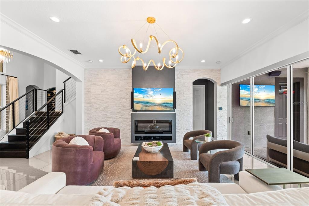 A living room features a fireplace, a wall-mounted television, and a modern gold chandelier — 1256 TYNE LANE, BRADENTON, FL