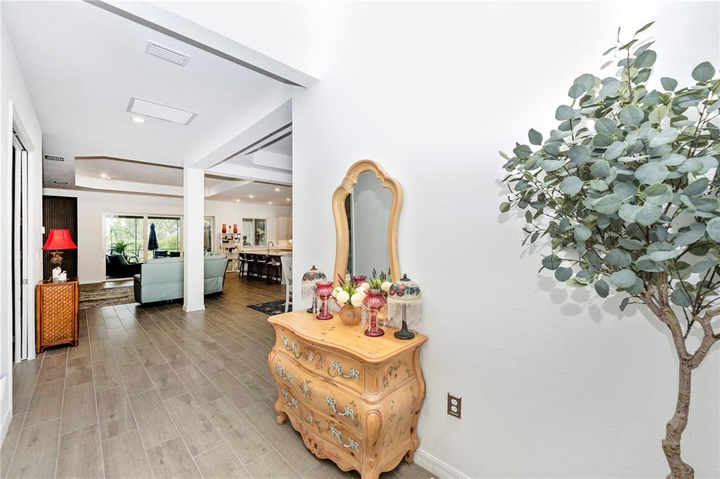 A hallway with wood-look tile flooring leads to an open living area and kitchen — 12845 TULUM LOOP, VENICE, FL