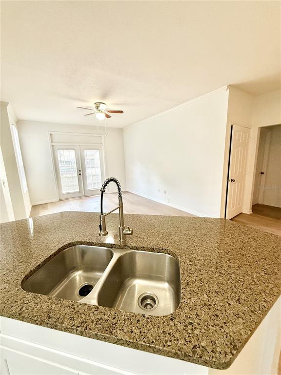 A kitchen island with a double-basin stainless steel sink overlooks a living area with French doors — 6356 RALEIGH STREET UNIT 1503, ORLANDO, FL