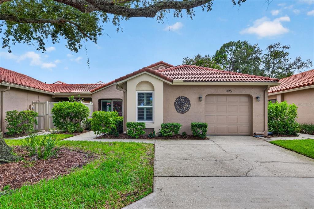 A single-story house with a tan stucco exterior, a tile roof, and an attached garage — 495 ST TROPEZ CIRCLE NE, ST PETERSBURG, FL