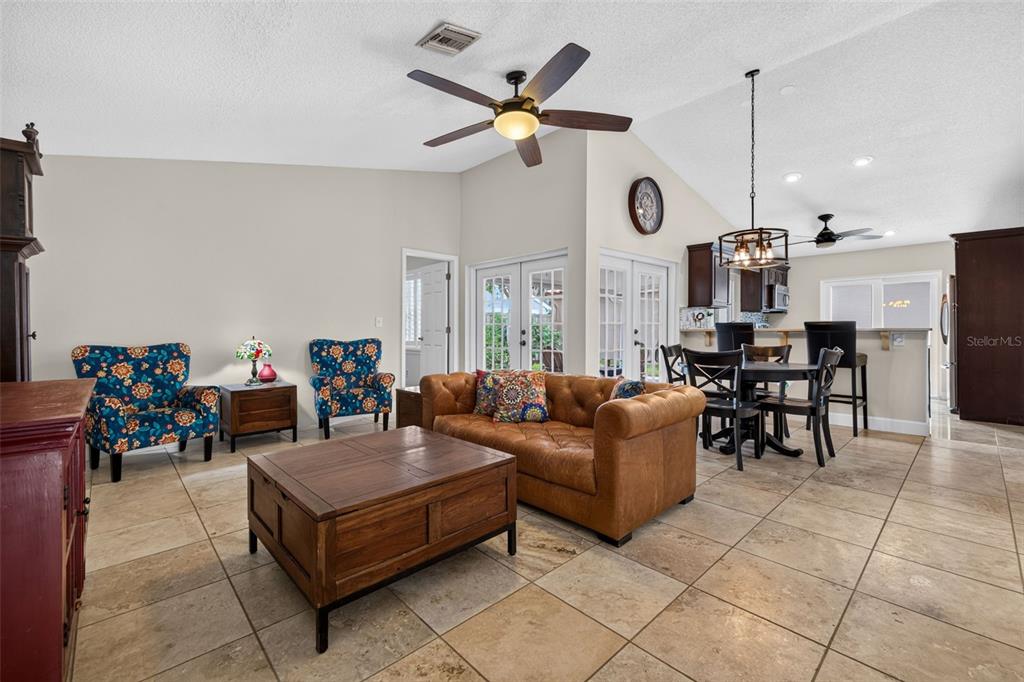 A living room with tile floors, a brown leather sofa, and a wooden coffee table — 495 ST TROPEZ CIRCLE NE, ST PETERSBURG, FL
