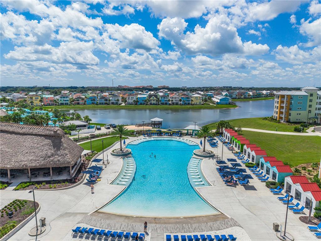An aerial view of a resort swimming pool with cabanas and a lake in the background — 3151 SUNSET WALK DRIVE UNIT 414, KISSIMMEE, FL