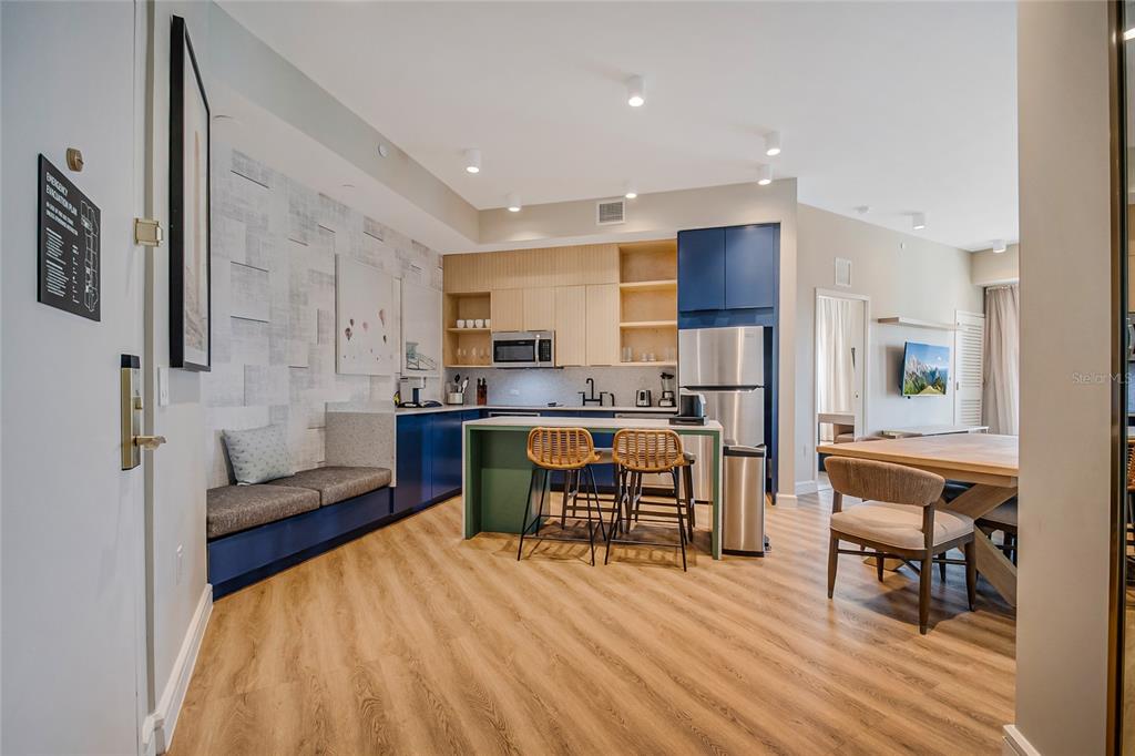 A modern kitchen features blue and wood cabinetry, a green island, and a built-in bench — 3151 SUNSET WALK DRIVE UNIT 414, KISSIMMEE, FL