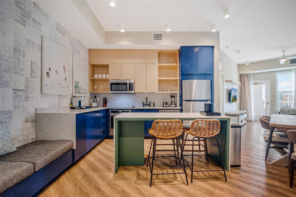 A modern kitchen features blue cabinets, light wood accents, a breakfast island, and adjacent bench seating — 3151 SUNSET WALK DRIVE UNIT 414, KISSIMMEE, FL