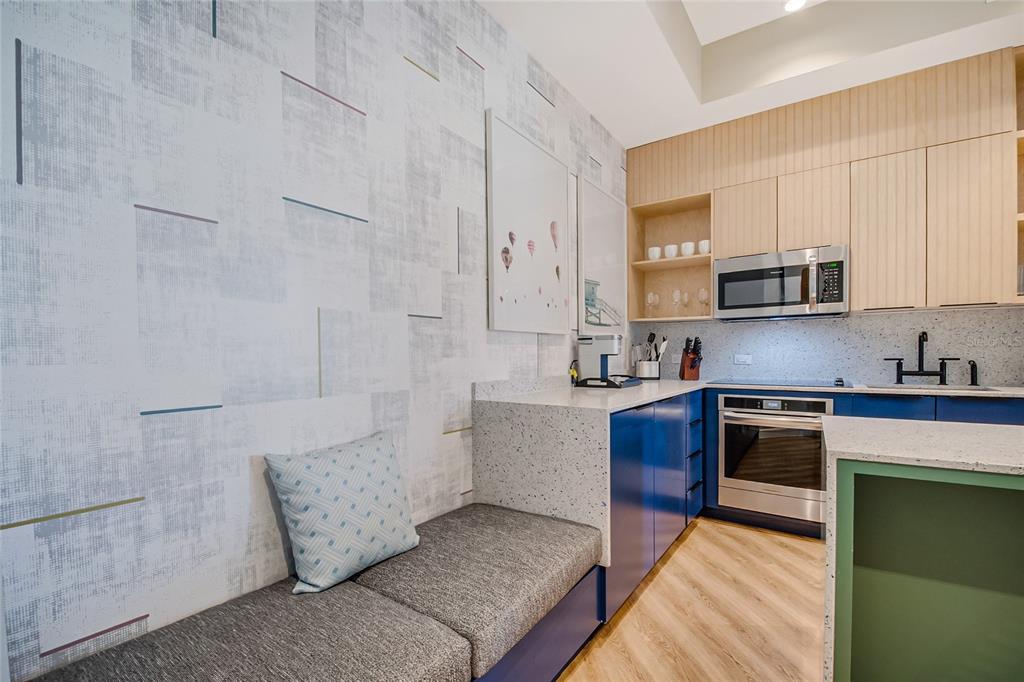 A modern kitchen features blue cabinetry, speckled countertops, a built-in bench seat, and patterned wallpaper — 3151 SUNSET WALK DRIVE UNIT 414, KISSIMMEE, FL