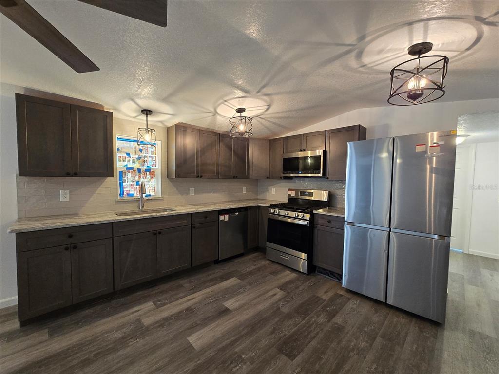 A kitchen featuring dark wood cabinets, stainless steel appliances, and wood-look flooring — 43541 DIXIE DRIVE, PAISLEY, FL