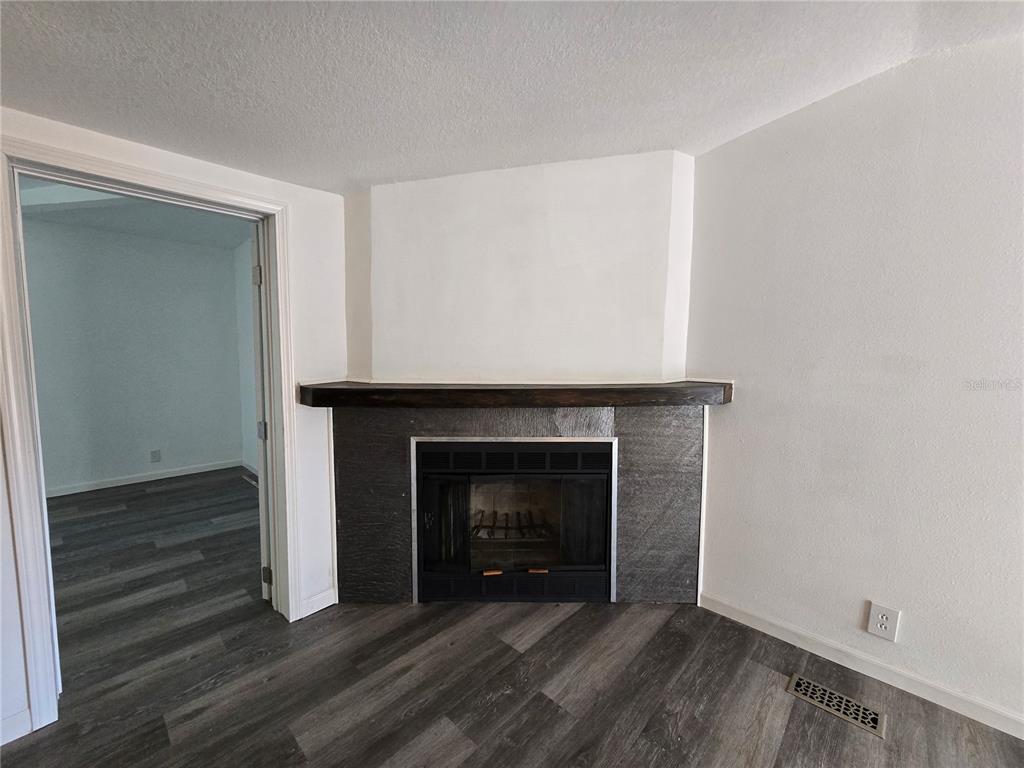 A corner fireplace with dark stone tile and a wood mantel in a room — 43541 DIXIE DRIVE, PAISLEY, FL