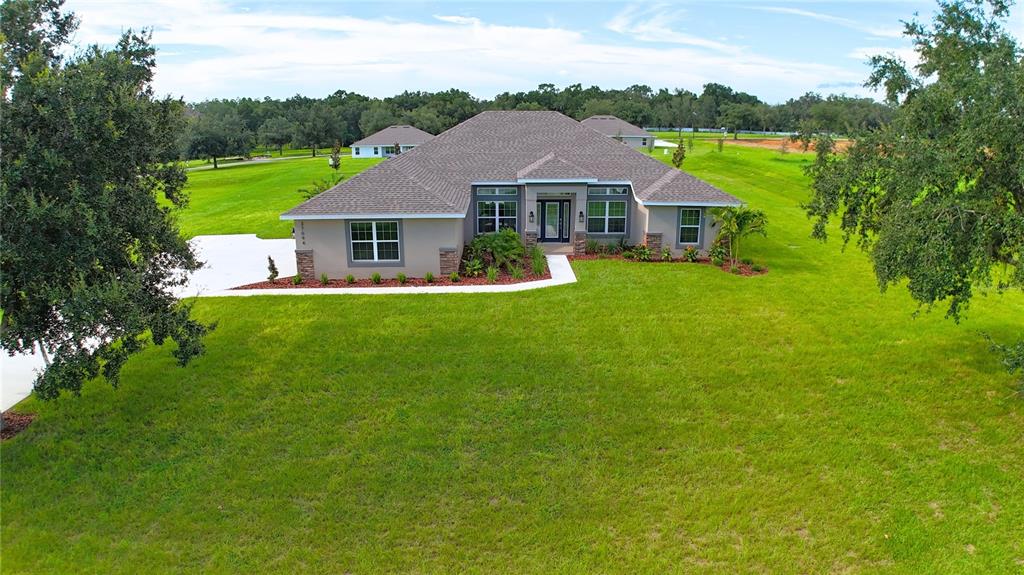 A single-story house with a tan exterior sits on a large, grassy lot — 37094 HIDDEN VIEW CIRCLE, DADE CITY, FL