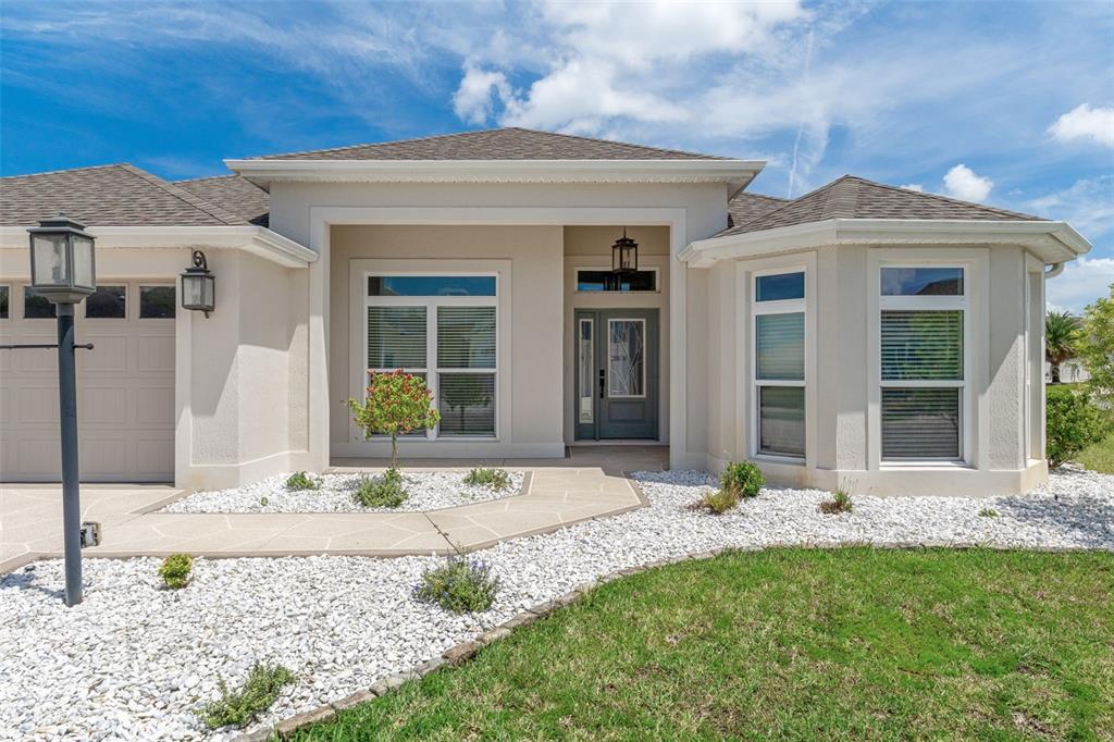 A single-story beige house with a two-car garage and a landscaped front yard — 3037 LICCIARDELLO PATH, THE VILLAGES, FL