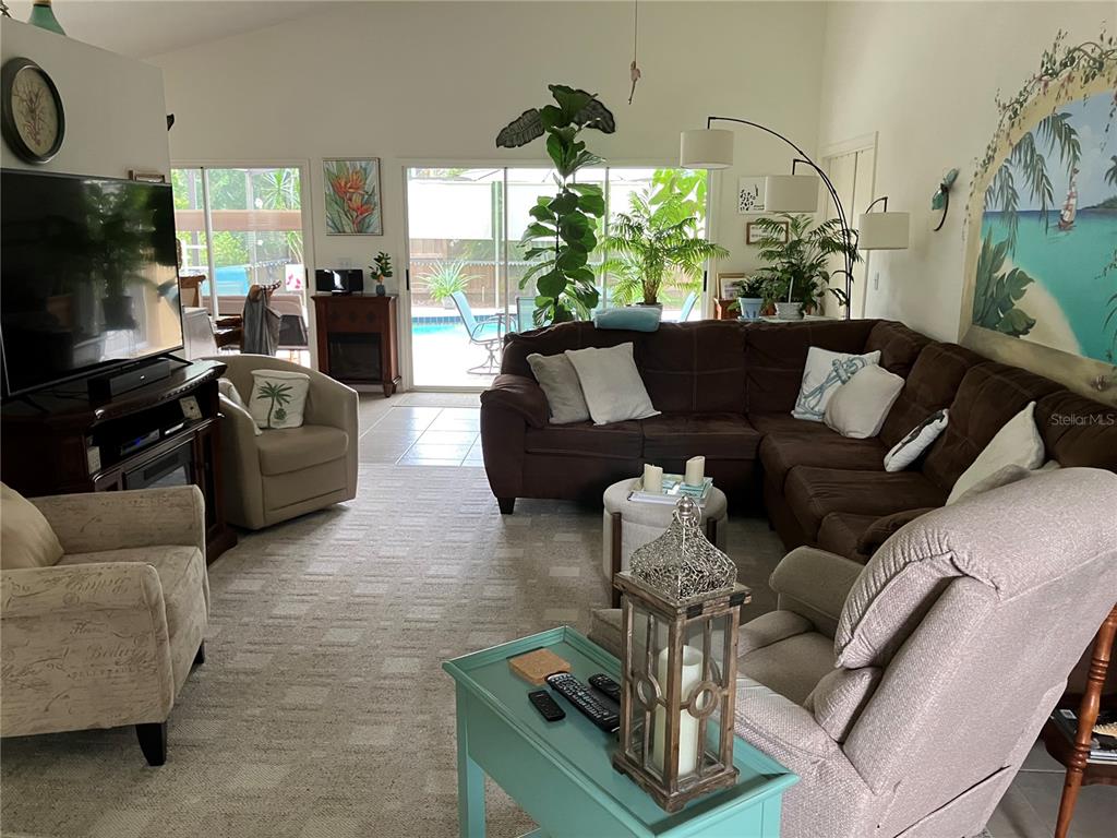 A living room features a large brown sectional, a mural, and sliding glass doors — 5406 83RD TERRACE E, SARASOTA, FL
