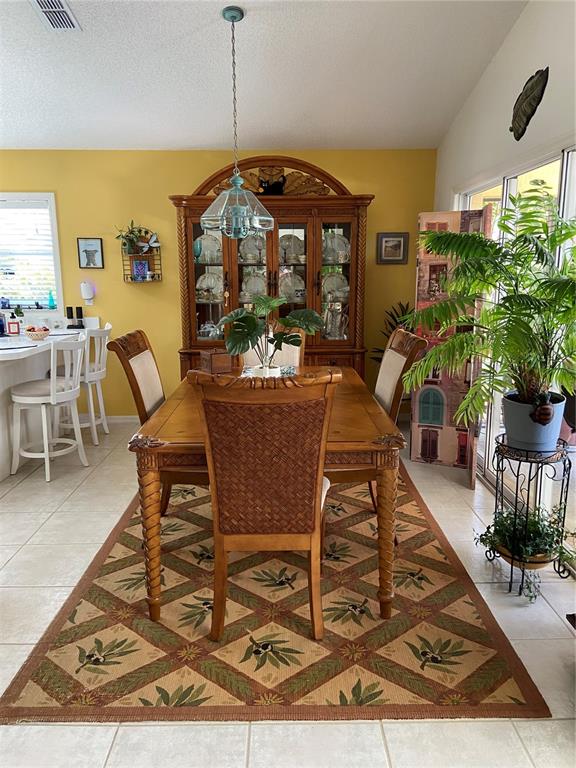 A kitchen with white cabinets, tile flooring, a stainless steel refrigerator, and a wooden island — 5406 83RD TERRACE E, SARASOTA, FL
