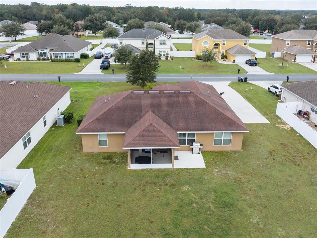 An aerial view of a suburban house with a brown shingled roof and backyard patio — 5749 SW 98TH PLACE, OCALA, FL