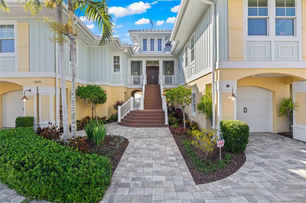 A two-story house with light blue and yellow siding features a central elevated entryway — 12271 SHOREVIEW DRIVE, MATLACHA, FL