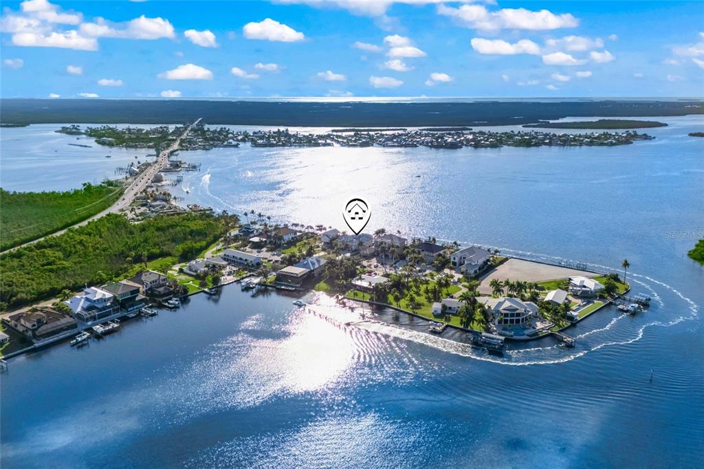 An aerial view shows a coastal residential community surrounded by water with a bridge nearby — 12271 SHOREVIEW DRIVE, MATLACHA, FL