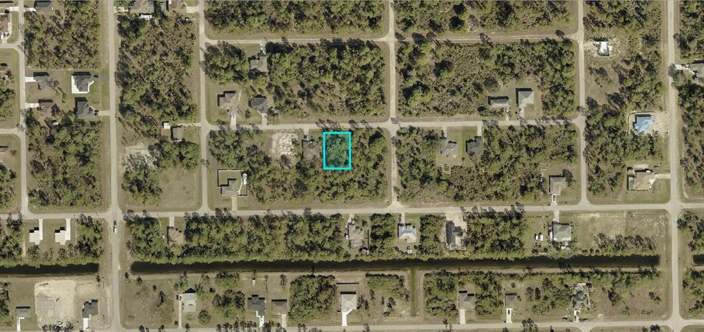An aerial view shows a vacant, rectangular lot highlighted in blue within a residential neighborhood — 1024 CARROLL STREET E, LEHIGH ACRES, FL
