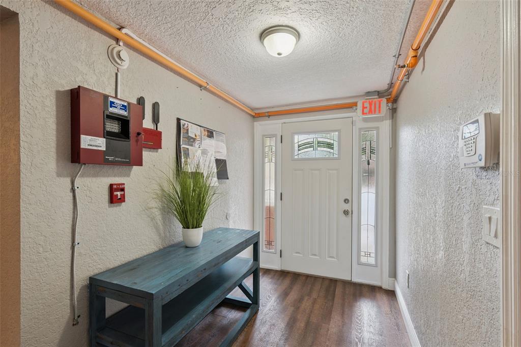 A hallway features wood-look flooring, a blue console table, and a wall-mounted fire alarm panel — 78 S WINTER PARK DRIVE, CASSELBERRY, FL