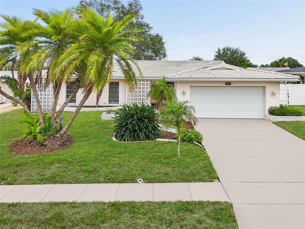 A single-story house with a light pink exterior, a palm tree, and a decorative screen wall — 14363 NEPTUNE ROAD, SEMINOLE, FL