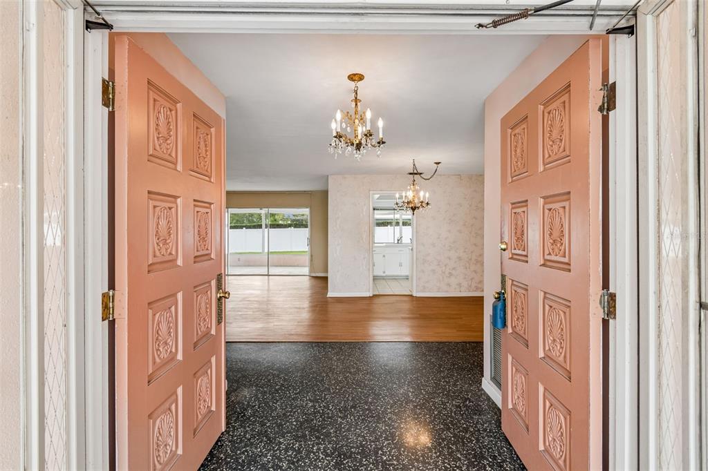 A living and dining area with wood-look flooring, wallpapered walls, and a crystal chandelier — 14363 NEPTUNE ROAD, SEMINOLE, FL