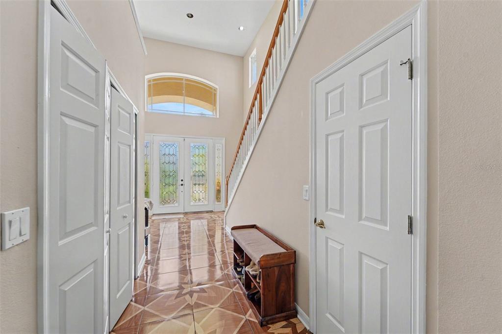 A bright foyer features tiled floors, a wooden staircase, and a double front door — 10409 CANARY ISLE DRIVE, TAMPA, FL
