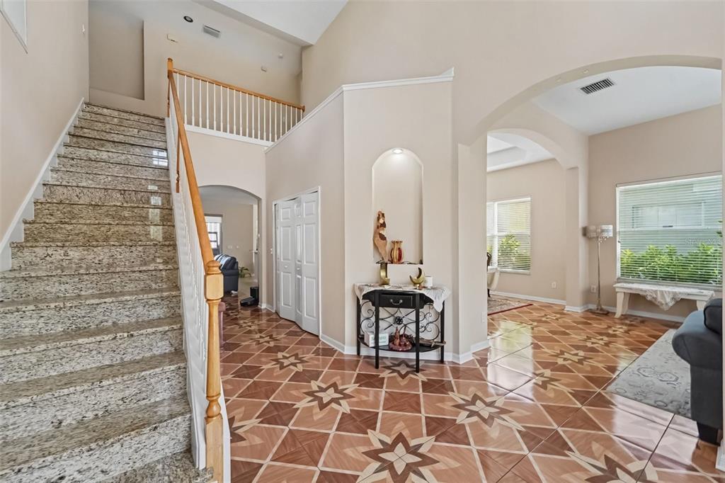 A foyer features a granite staircase, patterned tile flooring, and an arched wall niche — 10409 CANARY ISLE DRIVE, TAMPA, FL