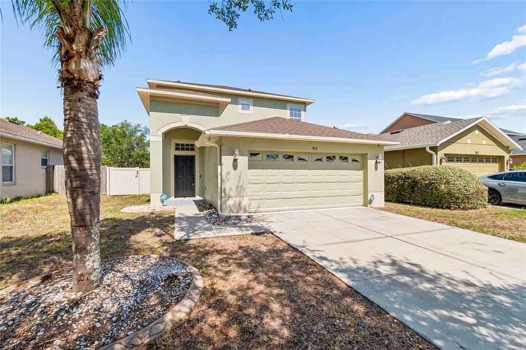 A two-story, light green stucco house features a two-car garage and a palm tree — 915 WINDTON OAK DRIVE, RUSKIN, FL