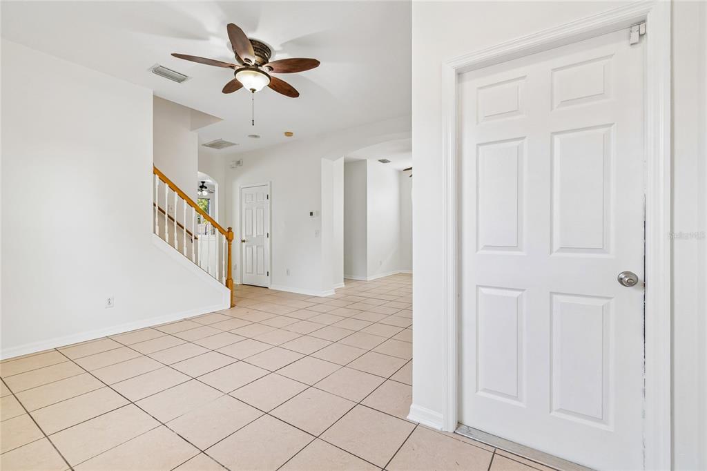 An interior view of a tiled room with a staircase, ceiling fan, and white doors — 915 WINDTON OAK DRIVE, RUSKIN, FL