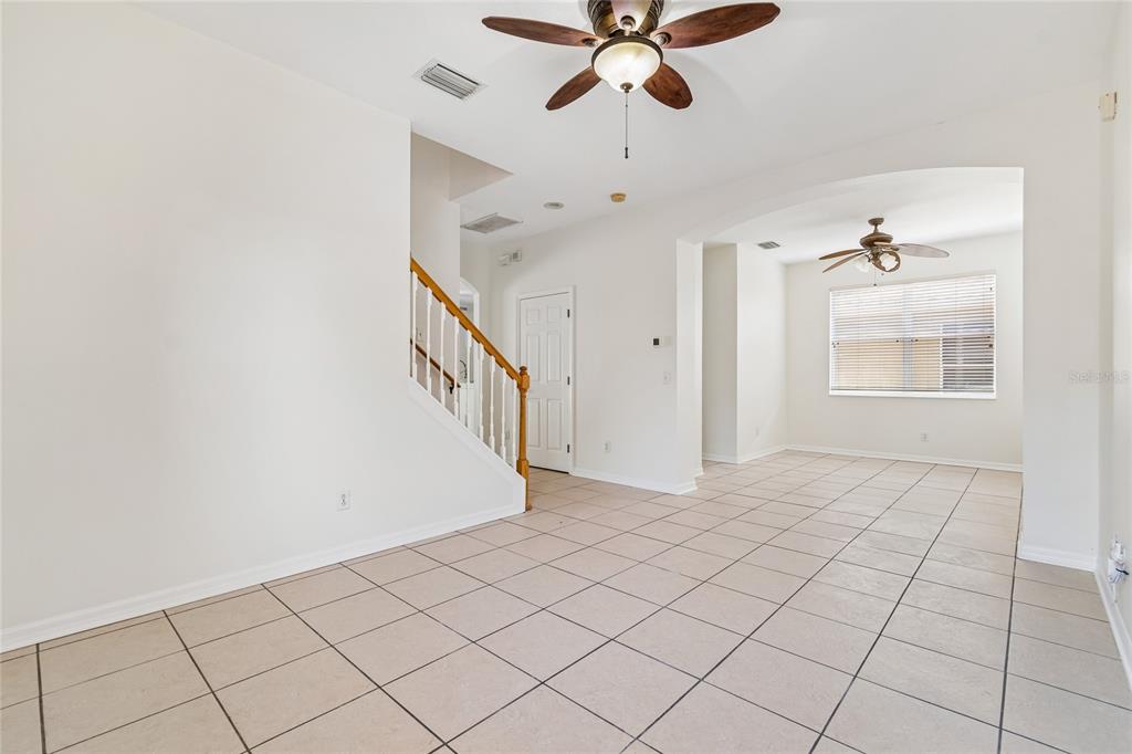 An interior view of a room with tile flooring, a staircase, and two ceiling fans — 915 WINDTON OAK DRIVE, RUSKIN, FL