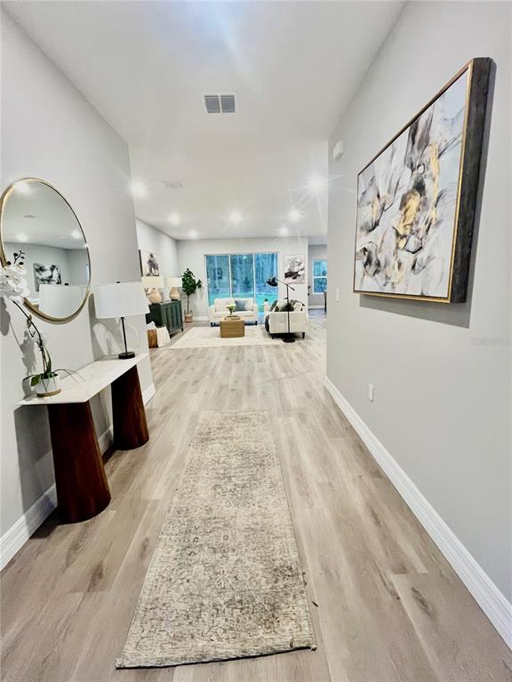 A long entryway with light wood flooring leads into an open-concept living area — 6 BELLIS COURT, HOMOSASSA, FL