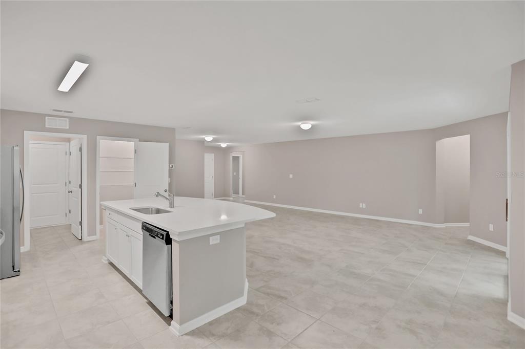 A kitchen island with a stainless steel dishwasher sits in an open-concept room with tile — 2760 LAUREL FALLS DRIVE, GREEN COVE SPRINGS, FL