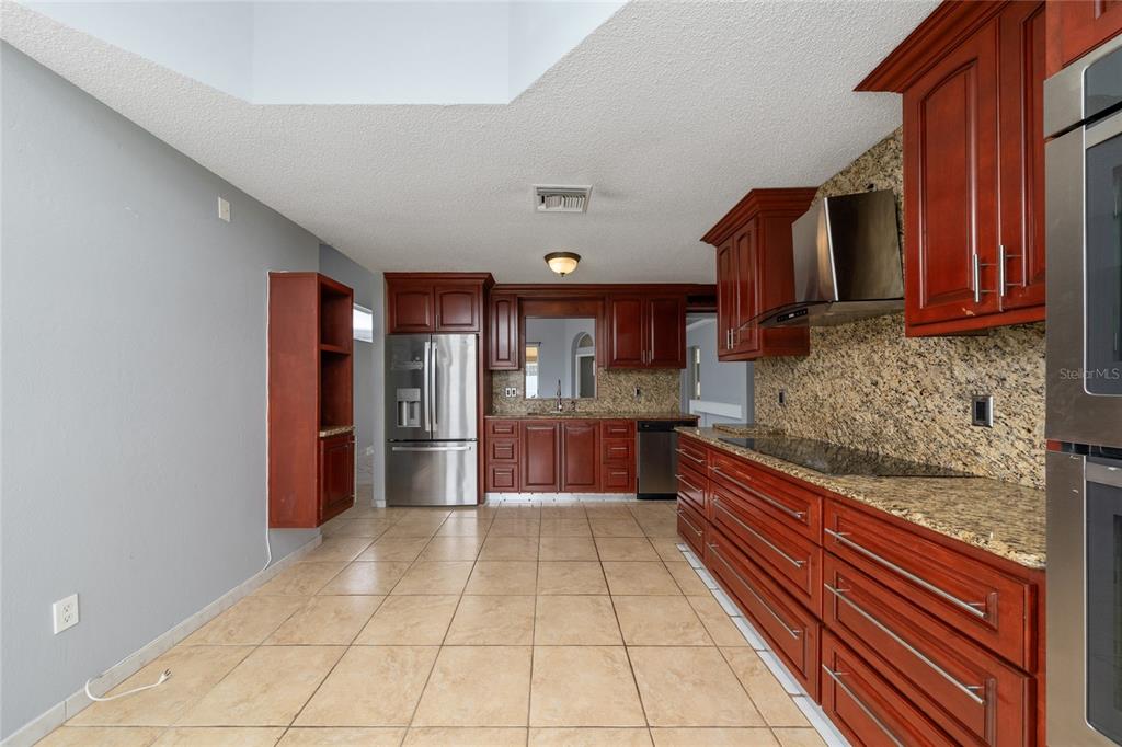 An aerial view shows a single-story suburban house with a gray roof and driveway — 8810 KENSINGTON COURT, KISSIMMEE, FL
