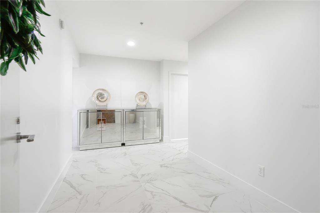 A bright entryway features white marble-look tile flooring and a mirrored console table — 175 1ST STREET S UNIT 1008, ST PETERSBURG, FL