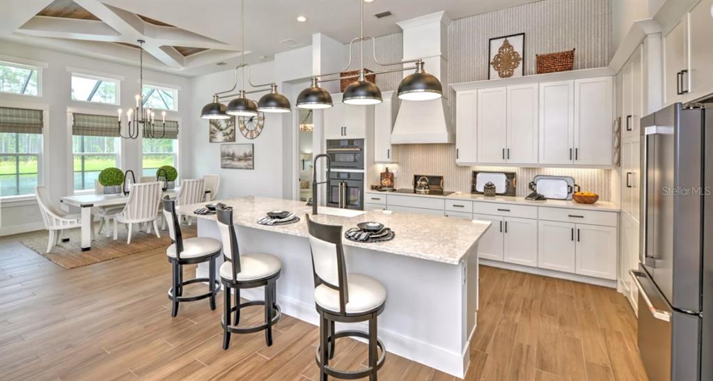 A modern kitchen features white cabinetry, a large quartz island, and pendant lighting — 54 NEWCASTLE LANE, ORMOND BEACH, FL