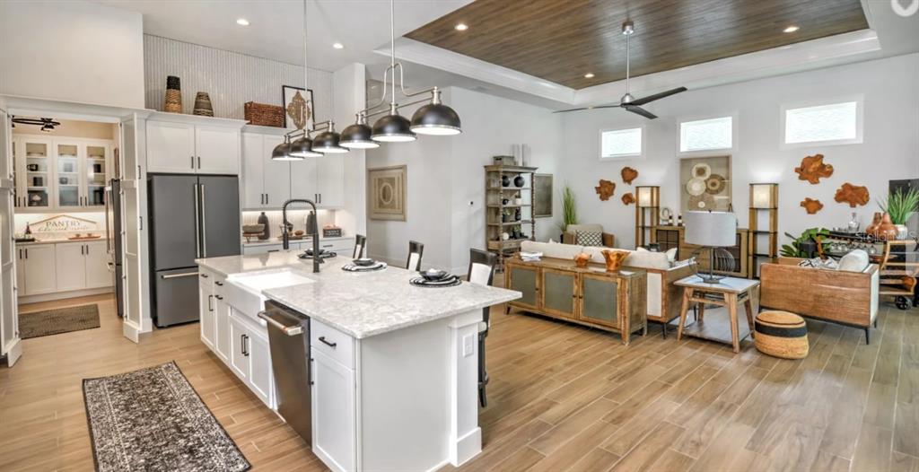 A modern open-concept kitchen and living area with white cabinetry, wood flooring, and pendant lighting — 54 NEWCASTLE LANE, ORMOND BEACH, FL