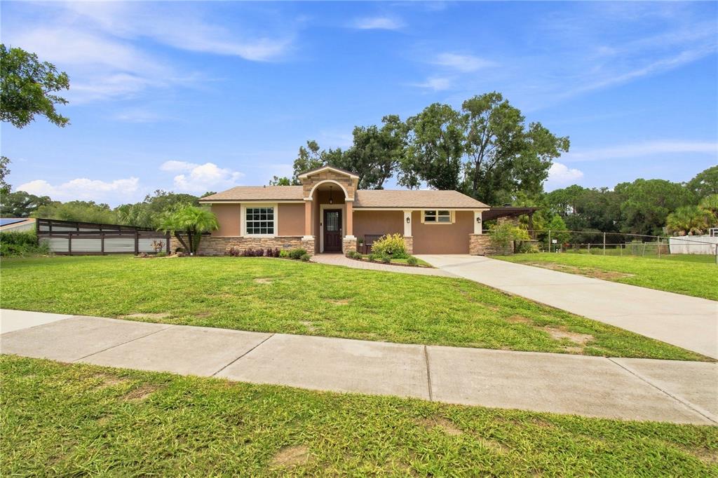 A single-story house with a stone-accented entrance, a concrete driveway, and a grassy front yard — 9020 AUBURN WAY, TAMPA, FL