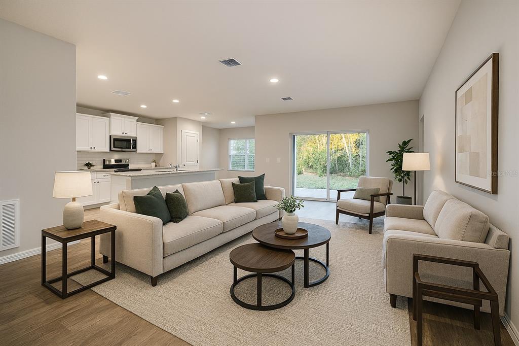 A living room with light-colored sofas, a round coffee table, and an open-concept kitchen — 2087 W SHINING DAWN LANE, LECANTO, FL