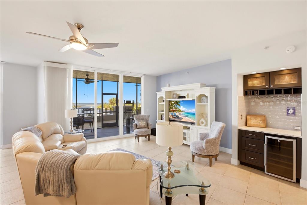 A living room features a beige sectional, a wet bar, and a balcony with water views — 3313 SUNSET KEY CIRCLE UNIT 105, PUNTA GORDA, FL