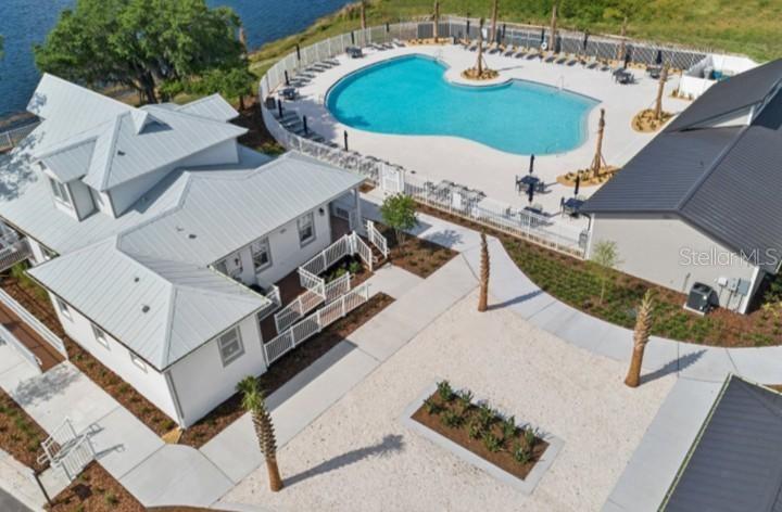 An aerial view shows a white building with a metal roof beside a swimming pool — 5692 STEPHENS ROAD, ST CLOUD, FL