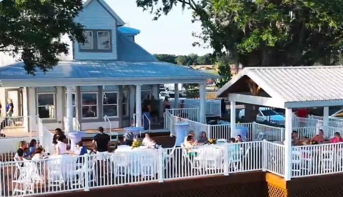 An outdoor deck with tables and white railings surrounds a blue house and pavilion — 5692 STEPHENS ROAD, ST CLOUD, FL