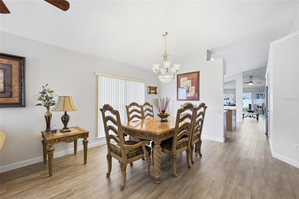 A dining room features a wooden table, six chairs, a chandelier, and light wood flooring — 115 N WEATHERSFIELD AVENUE, ALTAMONTE SPRINGS, FL
