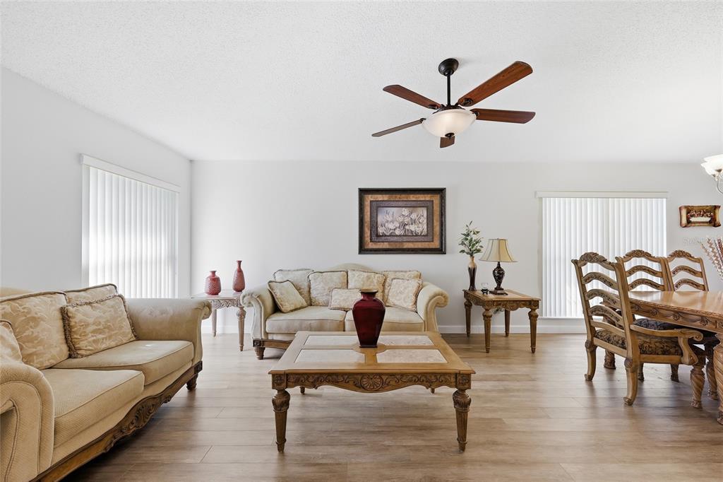 A living room with light wood-look flooring, a beige sofa, a coffee table, and dining furniture — 115 N WEATHERSFIELD AVENUE, ALTAMONTE SPRINGS, FL