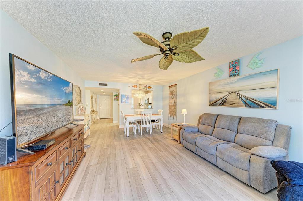 A living room with light wood-look flooring, a gray sofa, a television, and a ceiling fan — 3980 IRONWOOD CIRCLE UNIT 206, BRADENTON, FL
