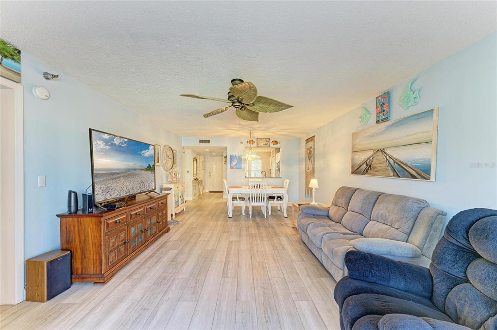 A living room and dining area feature light wood-look flooring, a ceiling fan, and furniture — 3980 IRONWOOD CIRCLE UNIT 206, BRADENTON, FL