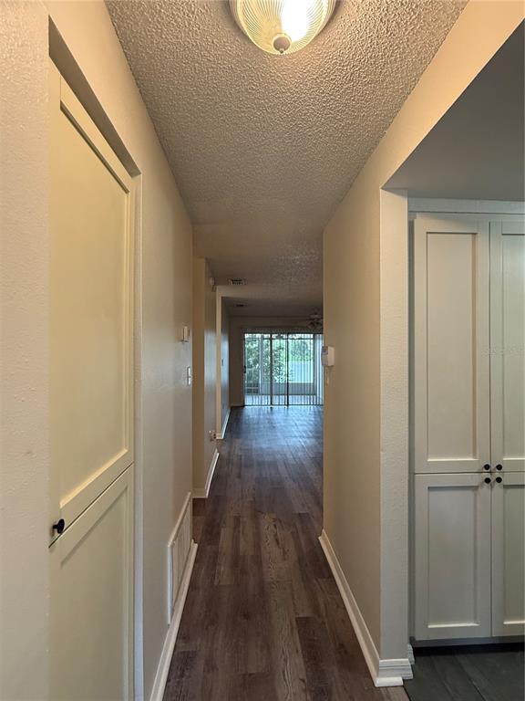 A hallway with wood-look flooring leads toward a glass sliding door and a screened patio — 702 COUNTRY LANE NE UNIT 702, WINTER HAVEN, FL