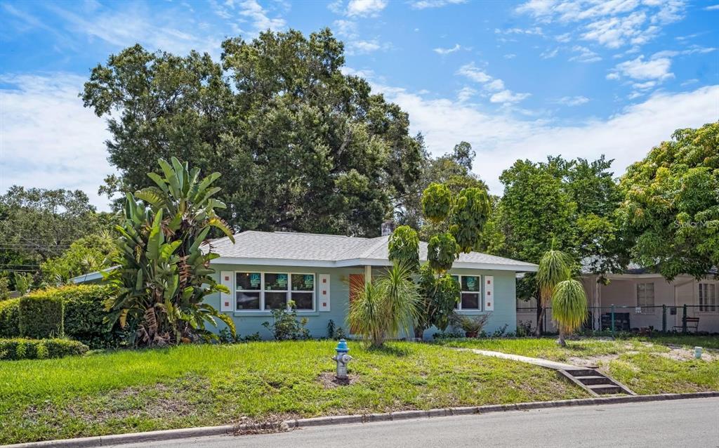 A single-story light green house with a front lawn, a fire hydrant, and mature trees — 617 26TH STREET W, BRADENTON, FL