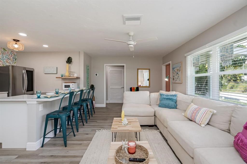 A living room and kitchen area with a white sectional sofa, breakfast bar, and stools — 617 26TH STREET W, BRADENTON, FL