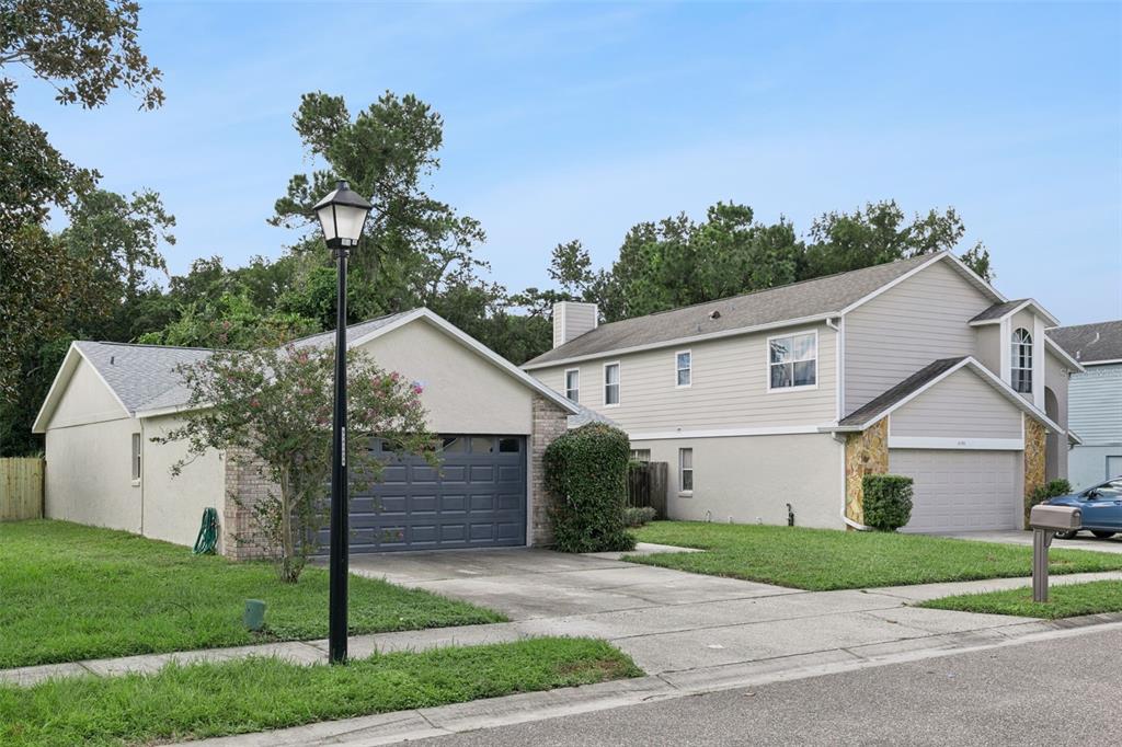 A view of two adjacent suburban houses with driveways and garages from the street — 1052 BRIELLE AVENUE, OVIEDO, FL
