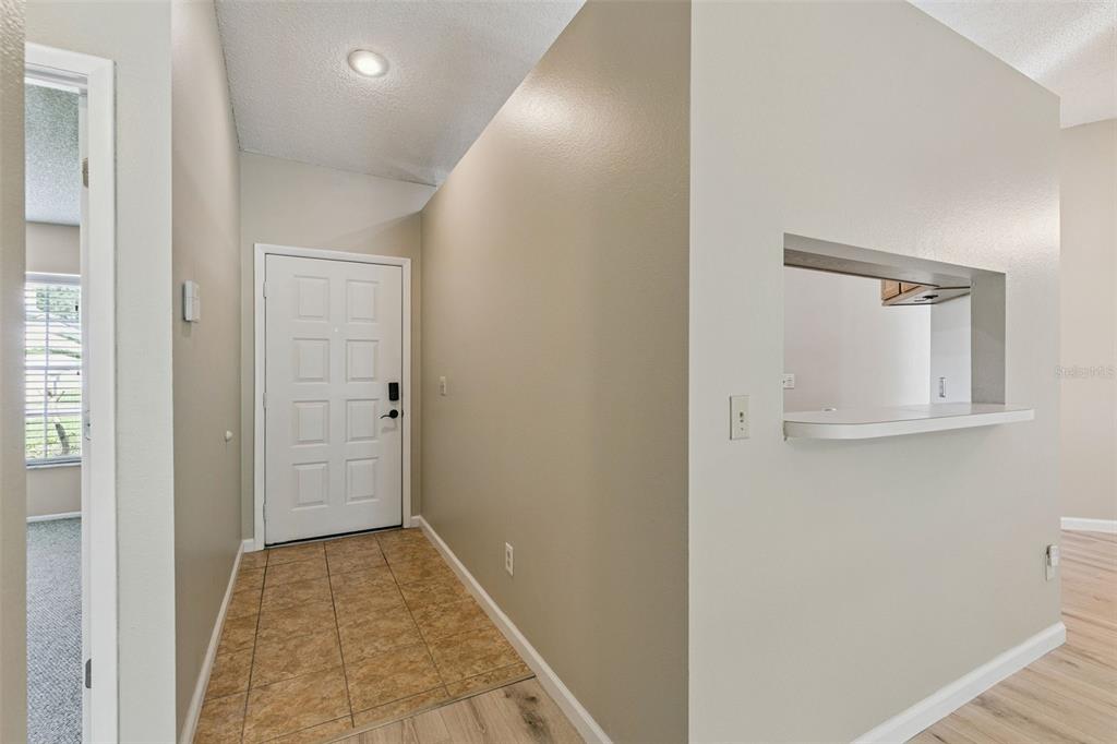 An entryway features a tiled floor, a white front door, and a kitchen pass-through window — 1052 BRIELLE AVENUE, OVIEDO, FL