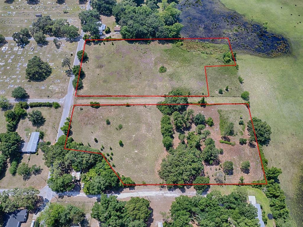 An aerial view shows two adjacent, undeveloped rectangular lots outlined in red near a cemetery — TBD E PARK STREET, CENTER HILL, FL